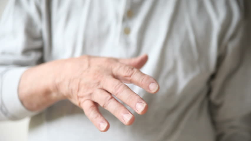 Pessoa jovem observando tremor nas mãos durante atividade cotidiana