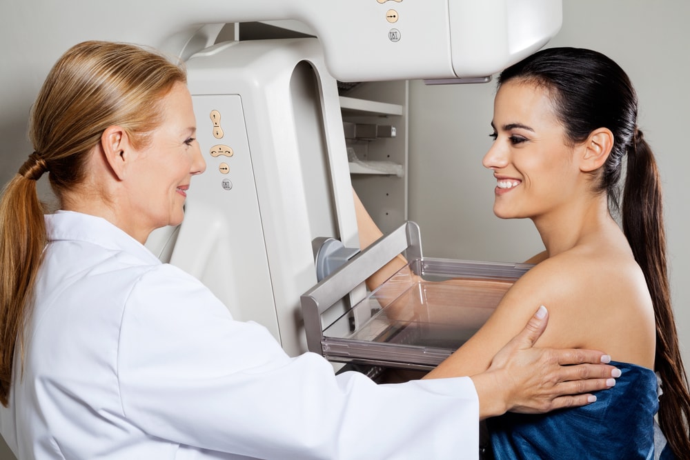 Técnica em radiologia acolhendo paciente sorridente durante a mamografia